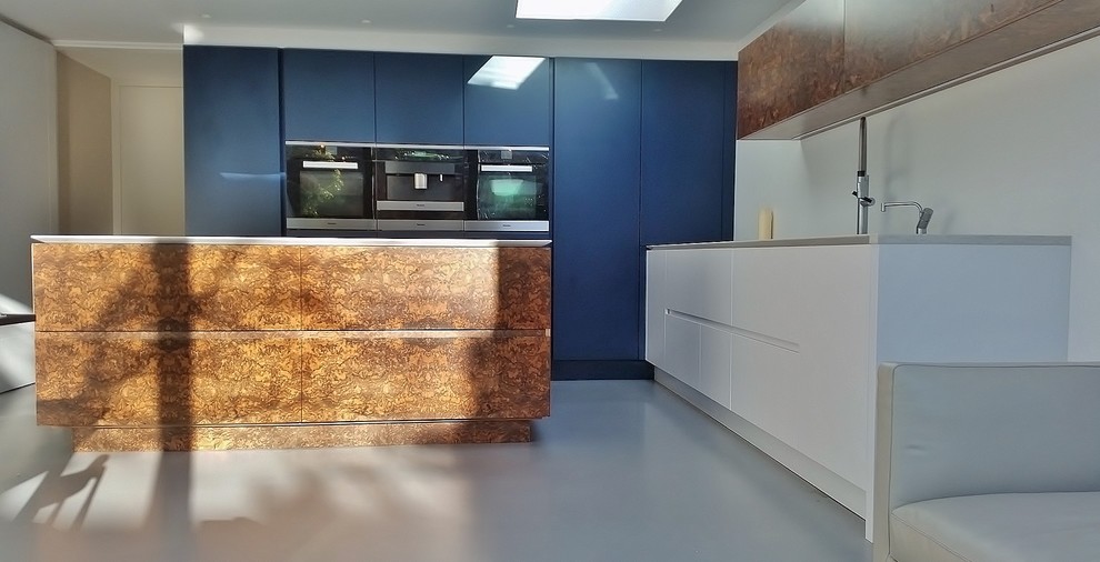 Photo of a medium sized contemporary l-shaped kitchen/diner in London with a submerged sink, flat-panel cabinets, dark wood cabinets, engineered stone countertops, white splashback, stainless steel appliances, concrete flooring and an island.