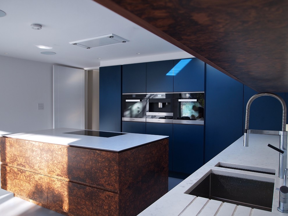 Inspiration for a medium sized contemporary l-shaped kitchen/diner in London with a submerged sink, flat-panel cabinets, blue cabinets, engineered stone countertops, black appliances, concrete flooring and an island.