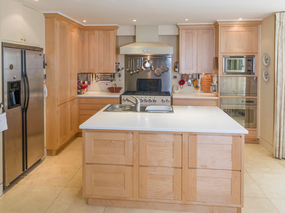 Mid-sized minimalist galley limestone floor open concept kitchen photo in Other with a triple-bowl sink, recessed-panel cabinets, light wood cabinets, solid surface countertops, metallic backsplash, stainless steel appliances and an island
