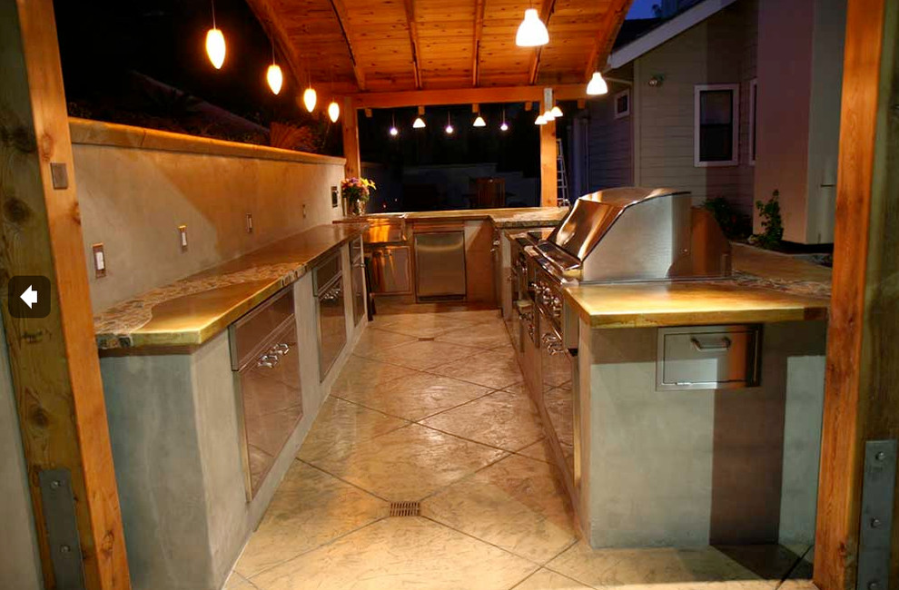 Foto på ett stort tropiskt kök, med en dubbel diskho, bänkskiva i betong, rostfria vitvaror, betonggolv och en halv köksö