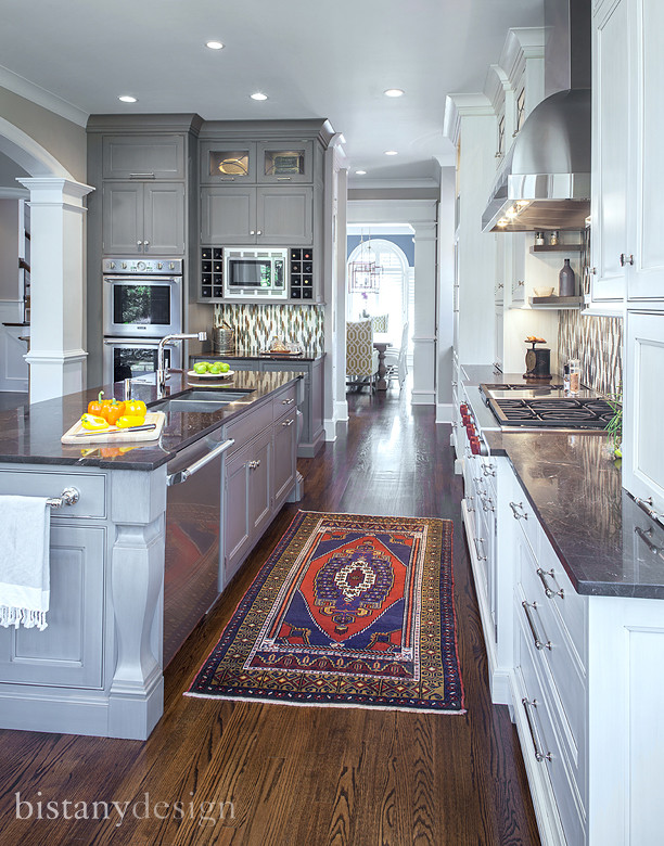 Example of a large transitional l-shaped medium tone wood floor eat-in kitchen design in Charlotte with stainless steel appliances, an island, an undermount sink, beaded inset cabinets, gray cabinets, granite countertops, multicolored backsplash and glass tile backsplash