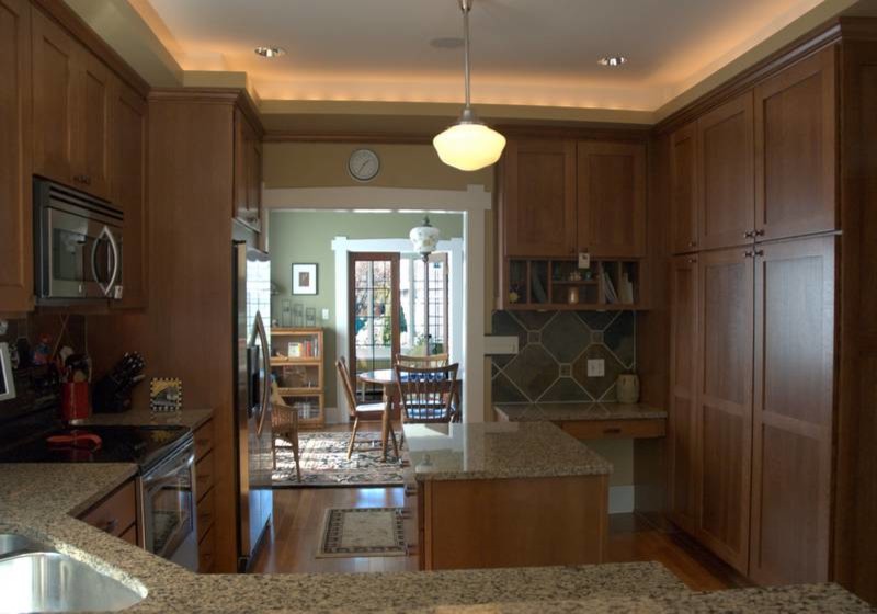 Inredning av ett klassiskt kök, med en undermonterad diskho, skåp i shakerstil, skåp i mellenmörkt trä, granitbänkskiva, grönt stänkskydd, stänkskydd i stenkakel och rostfria vitvaror