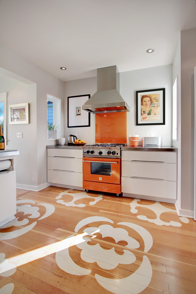 Enclosed kitchen - contemporary painted wood floor and multicolored floor enclosed kitchen idea in Seattle with flat-panel cabinets, white cabinets, orange backsplash, glass sheet backsplash, colored appliances and zinc countertops