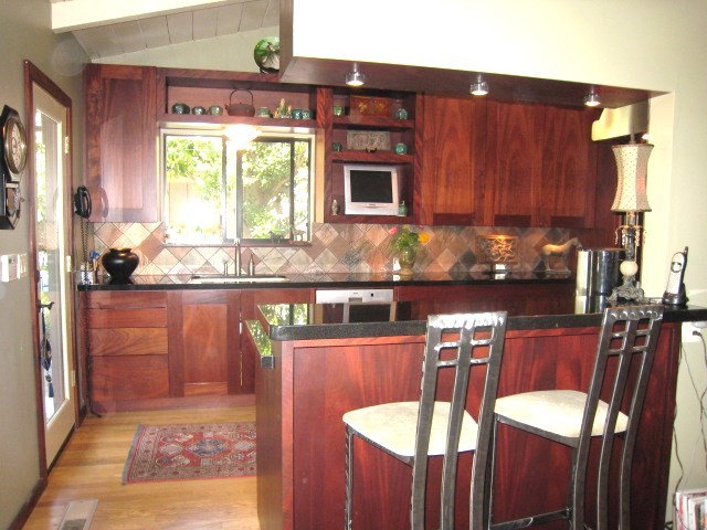 Modern inredning av ett mellanstort kök, med en undermonterad diskho, skåp i shakerstil, skåp i mörkt trä, granitbänkskiva, flerfärgad stänkskydd, rostfria vitvaror och mellanmörkt trägolv