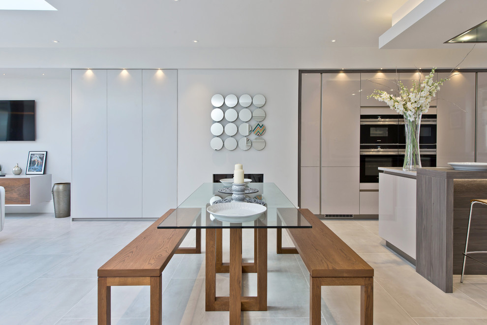 This is an example of a medium sized contemporary l-shaped kitchen/diner in London with a double-bowl sink, flat-panel cabinets, beige cabinets, quartz worktops, stainless steel appliances, marble flooring, an island and white floors.