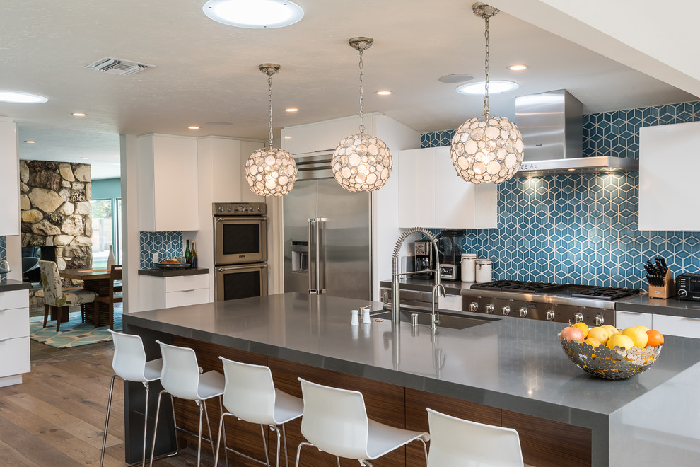 Esempio di una cucina design con lavello sottopiano, ante lisce, ante bianche, top in superficie solida, paraspruzzi blu, elettrodomestici in acciaio inossidabile, parquet scuro e pavimento marrone