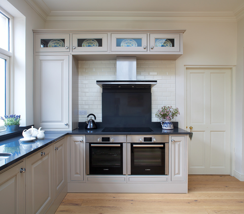 Elegant kitchen photo in Dublin with raised-panel cabinets, white backsplash, subway tile backsplash, stainless steel appliances, gray cabinets and granite countertops