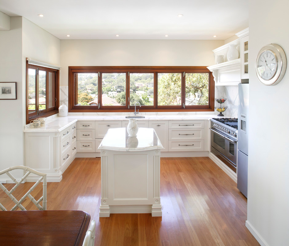 Idéer för ett mellanstort klassiskt kök, med en undermonterad diskho, luckor med infälld panel, vita skåp, marmorbänkskiva, vitt stänkskydd, stänkskydd i sten, rostfria vitvaror, mellanmörkt trägolv och en köksö