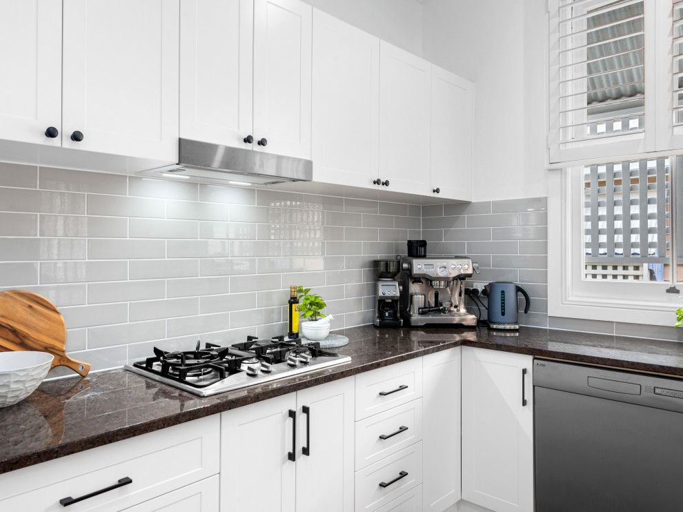 Photo of a large nautical u-shaped open plan kitchen in Brisbane with a submerged sink, recessed-panel cabinets, white cabinets, granite worktops, grey splashback, metro tiled splashback, stainless steel appliances and light hardwood flooring.