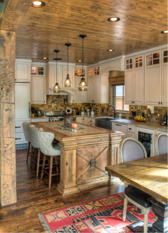 Photo of a large rustic l-shaped kitchen/diner in Minneapolis with a belfast sink, raised-panel cabinets, white cabinets, granite worktops, multi-coloured splashback, integrated appliances, dark hardwood flooring, an island, brown floors and wood splashback.