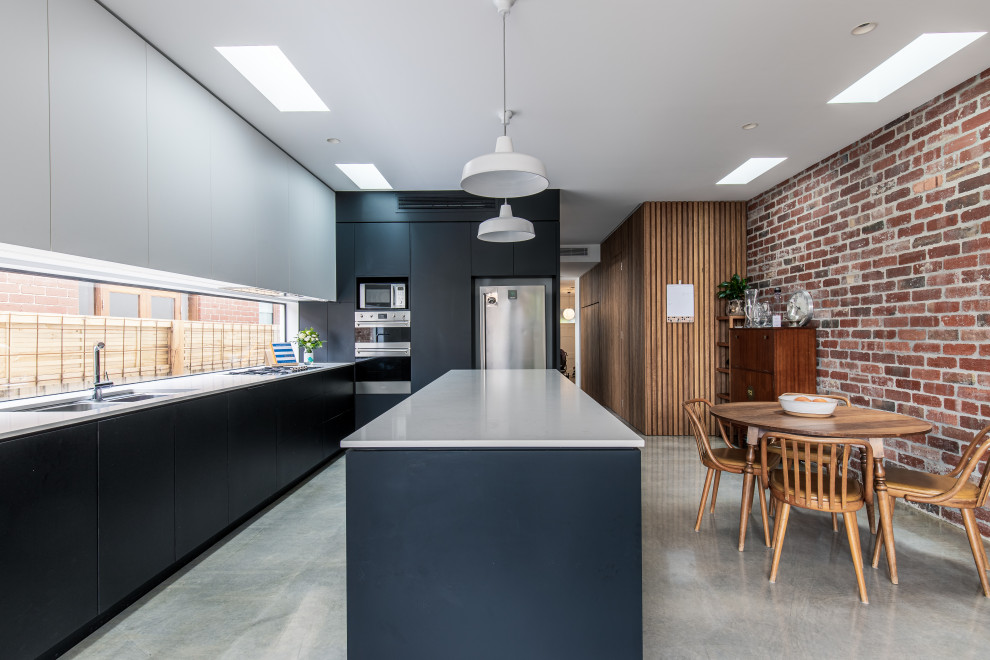 Ispirazione per una cucina design di medie dimensioni con lavello sottopiano, ante nere, top in quarzo composito, pavimento in cemento, pavimento grigio e top bianco