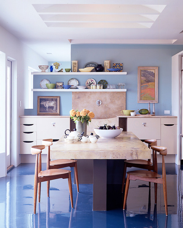 Cette photo montre une cuisine américaine moderne avec un placard à porte plane, des portes de placard beiges, plan de travail en marbre, une crédence bleue, sol en béton ciré, îlot et un sol bleu.