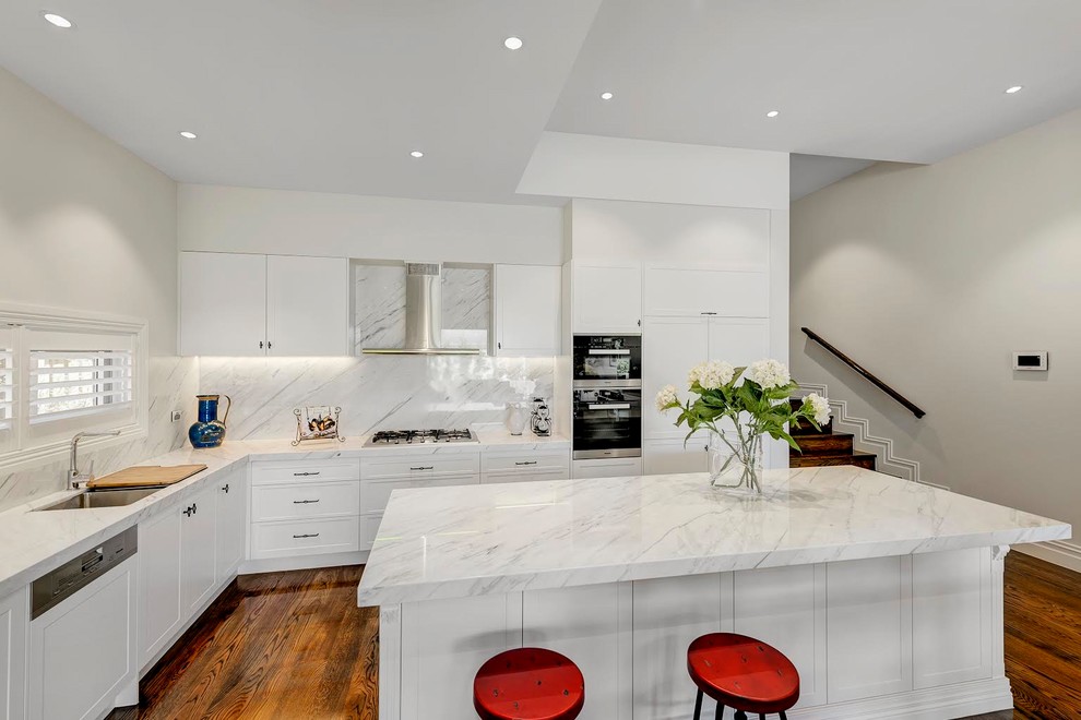 Exempel på ett mellanstort modernt kök, med luckor med profilerade fronter, vita skåp, marmorbänkskiva, vitt stänkskydd, stänkskydd i marmor, rostfria vitvaror, mellanmörkt trägolv, en köksö och en dubbel diskho