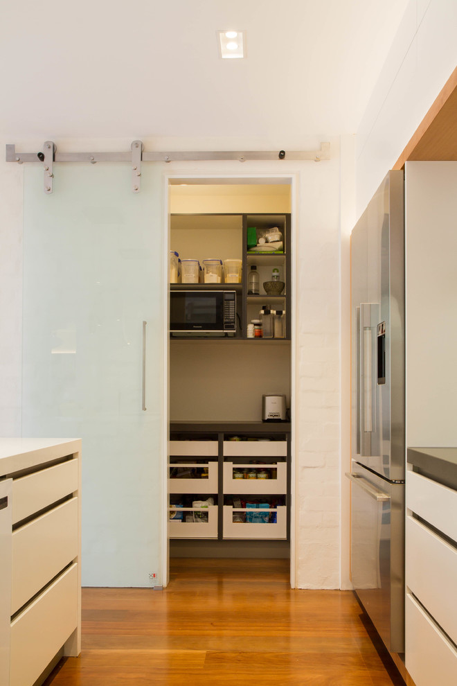 Ejemplo de cocina comedor actual grande con armarios con paneles lisos, puertas de armario blancas, encimera de cuarzo compacto y una isla
