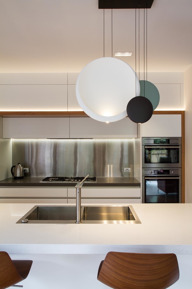 Photo of a large contemporary galley kitchen/diner in Melbourne with flat-panel cabinets, white cabinets, engineered stone countertops and an island.