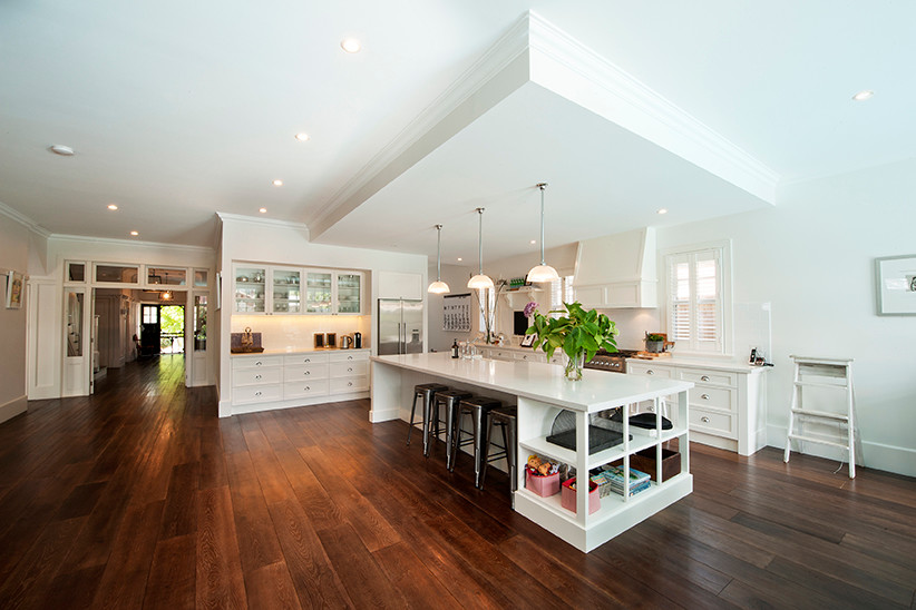 Foto på ett stort funkis kök med öppen planlösning, med en undermonterad diskho, vita skåp, granitbänkskiva, vitt stänkskydd, rostfria vitvaror, mörkt trägolv och en köksö