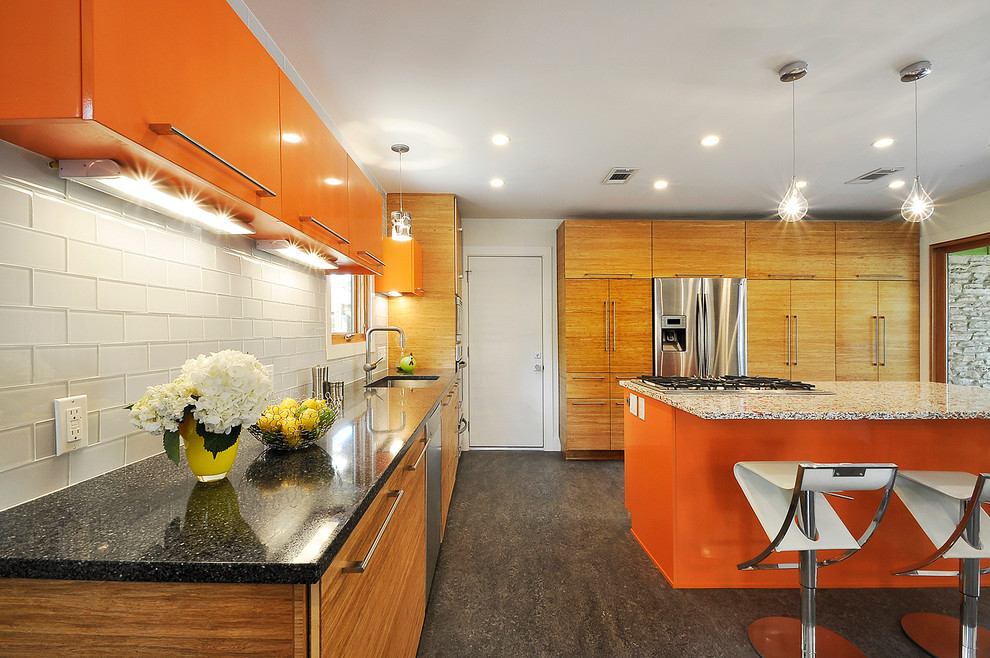 Ejemplo de cocina bohemia con fregadero bajoencimera, armarios con paneles lisos, puertas de armario naranjas, salpicadero blanco, salpicadero de azulejos de vidrio y electrodomésticos de acero inoxidable
