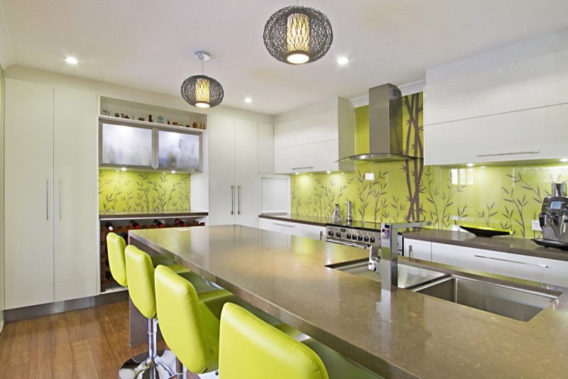 Exempel på ett mellanstort modernt kök, med bänkskiva i kvarts, grönt stänkskydd, glaspanel som stänkskydd, bambugolv och en köksö