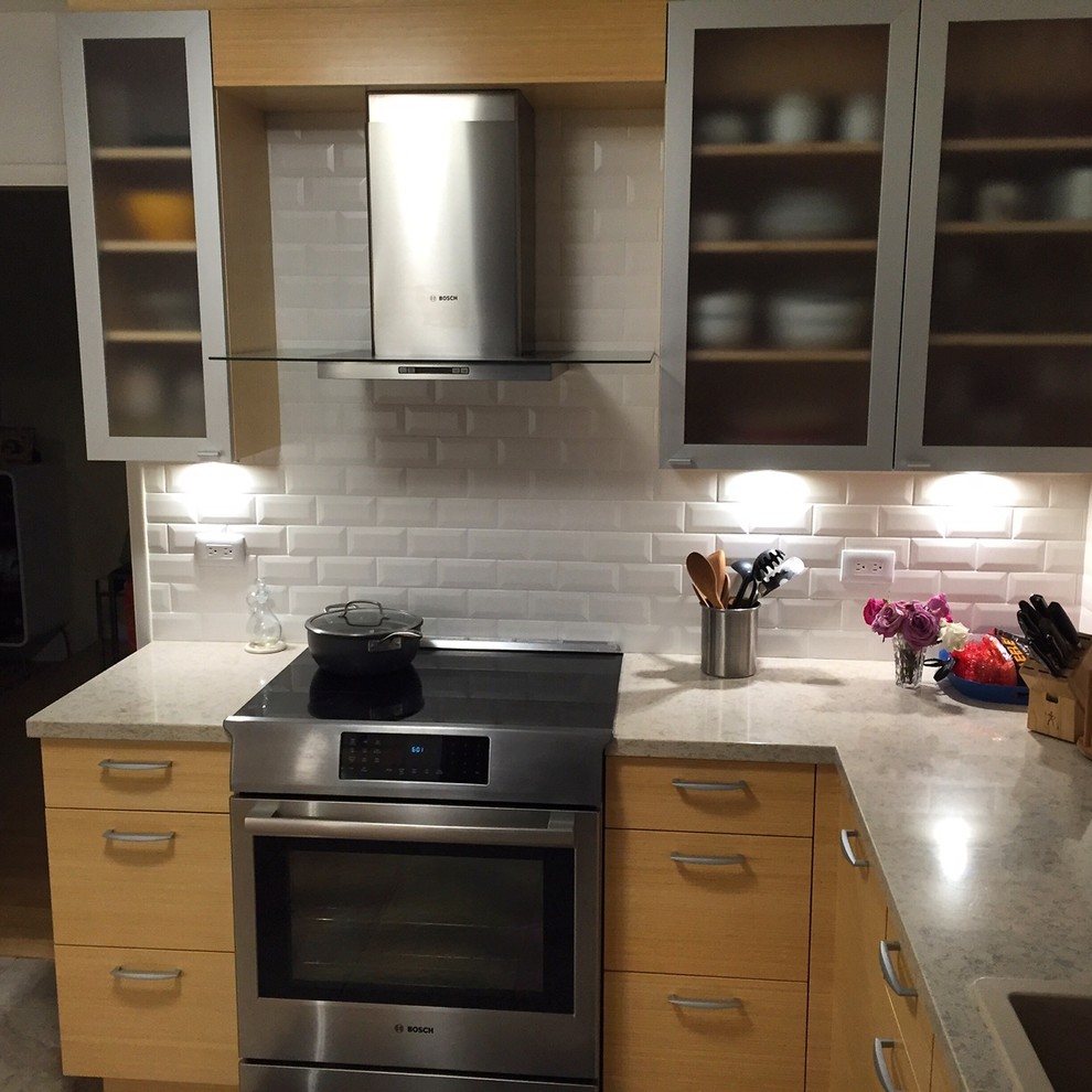 Moderne Küche mit flächenbündigen Schrankfronten, Quarzwerkstein-Arbeitsplatte, Küchenrückwand in Weiß, Rückwand aus Metrofliesen und Küchengeräten aus Edelstahl in Hawaii