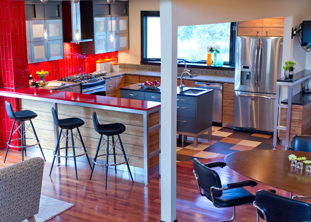 Foto på ett funkis kök, med en undermonterad diskho, släta luckor, grå skåp, bänkskiva i kvarts, rött stänkskydd, stänkskydd i glaskakel och rostfria vitvaror