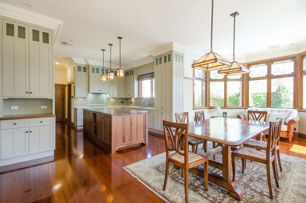 Example of a large arts and crafts u-shaped medium tone wood floor eat-in kitchen design in Melbourne with an undermount sink, shaker cabinets, beige cabinets, wood countertops, green backsplash, ceramic backsplash, stainless steel appliances and an island