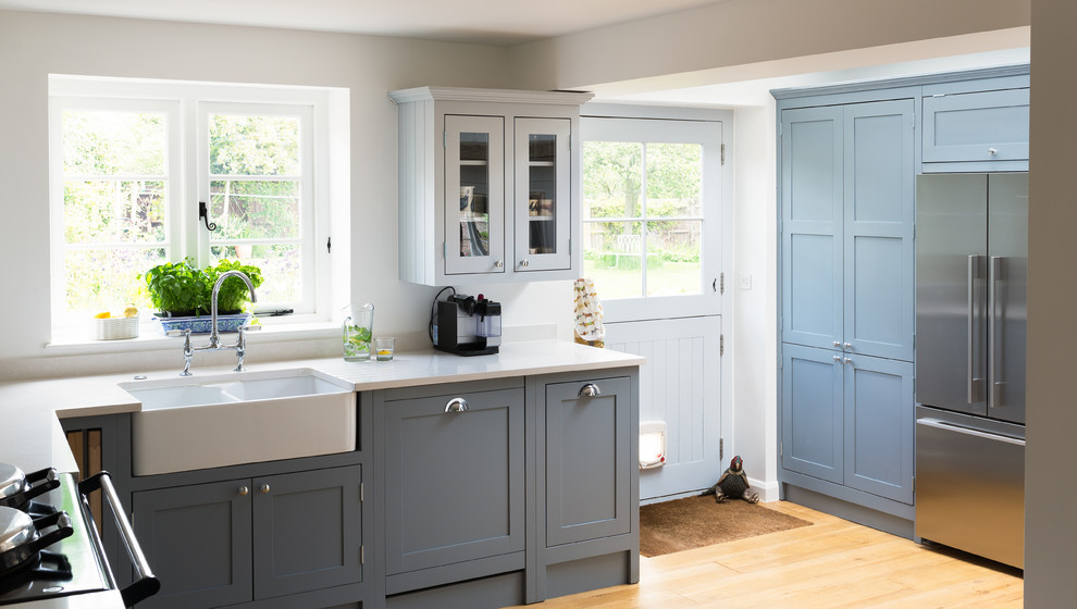 Foto de cocina comedor de estilo de casa de campo de tamaño medio sin isla con armarios estilo shaker, puertas de armario azules, encimera de cuarcita y suelo de madera clara