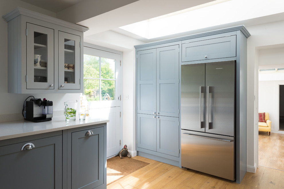 Design ideas for a medium sized country kitchen/diner in Gloucestershire with shaker cabinets, blue cabinets, quartz worktops, light hardwood flooring and no island.