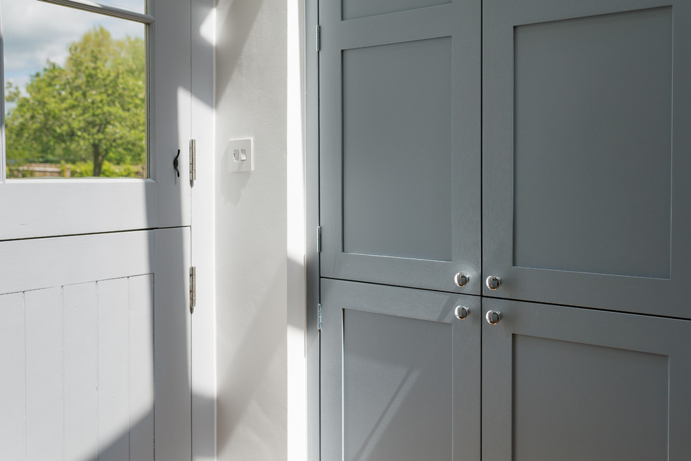 Diseño de cocina comedor de estilo de casa de campo de tamaño medio sin isla con armarios estilo shaker, puertas de armario azules, encimera de cuarcita y suelo de madera clara