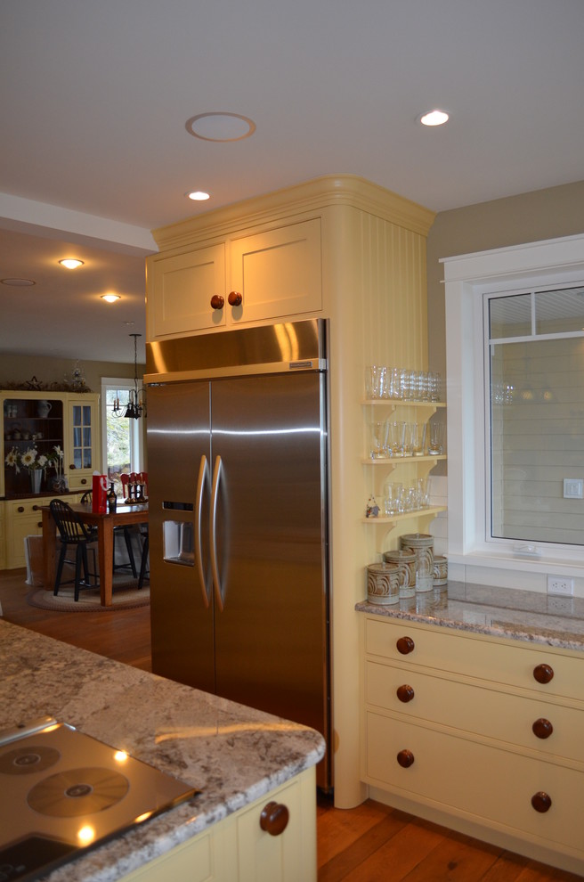 Inspiration for a timeless u-shaped kitchen remodel in Vancouver with a farmhouse sink, beaded inset cabinets, yellow cabinets, granite countertops, white backsplash, subway tile backsplash and stainless steel appliances