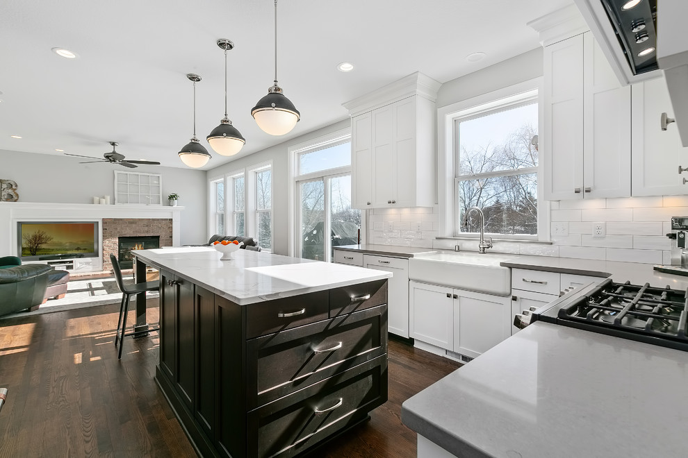 Exempel på ett mellanstort klassiskt vit vitt kök, med en rustik diskho, luckor med infälld panel, vita skåp, bänkskiva i kvartsit, vitt stänkskydd, stänkskydd i tunnelbanekakel, rostfria vitvaror, mörkt trägolv, en köksö och brunt golv