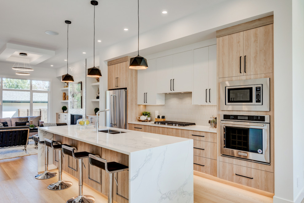 Mid-sized minimalist light wood floor open concept kitchen photo in Calgary with an undermount sink, flat-panel cabinets, light wood cabinets, quartzite countertops, gray backsplash, stainless steel appliances, an island and white countertops