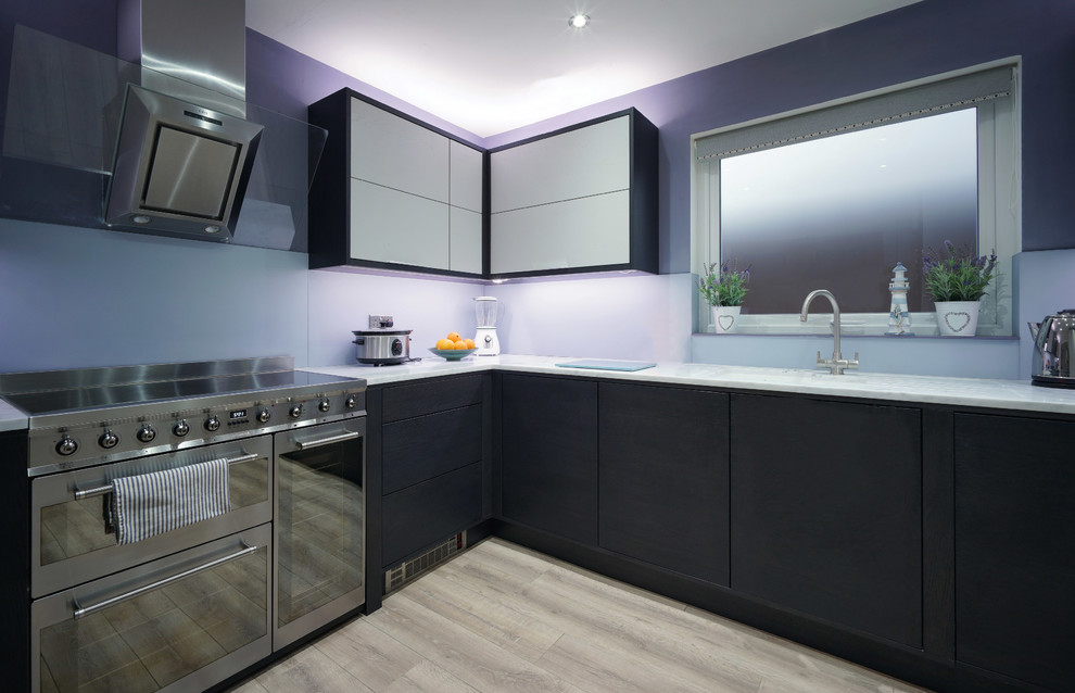 Medium sized modern l-shaped open plan kitchen in Other with an integrated sink, flat-panel cabinets, grey cabinets, composite countertops, grey splashback, glass sheet splashback, stainless steel appliances, laminate floors and no island.