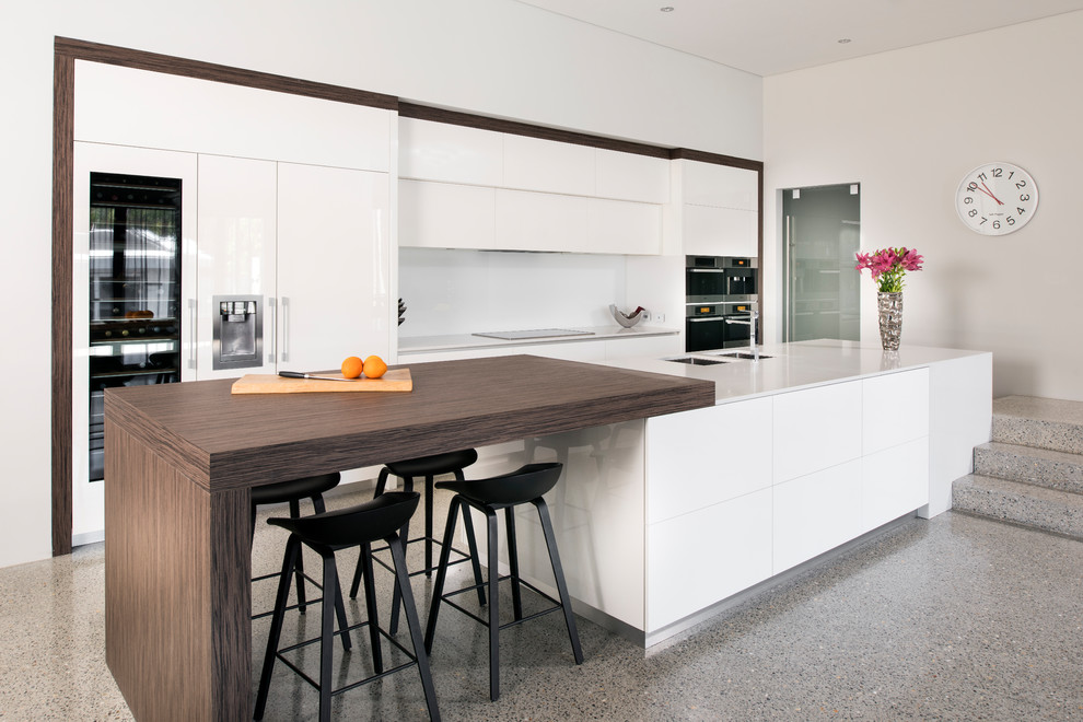 Foto di una cucina design con lavello a doppia vasca, ante lisce, ante bianche, paraspruzzi bianco, elettrodomestici da incasso, pavimento grigio e top bianco
