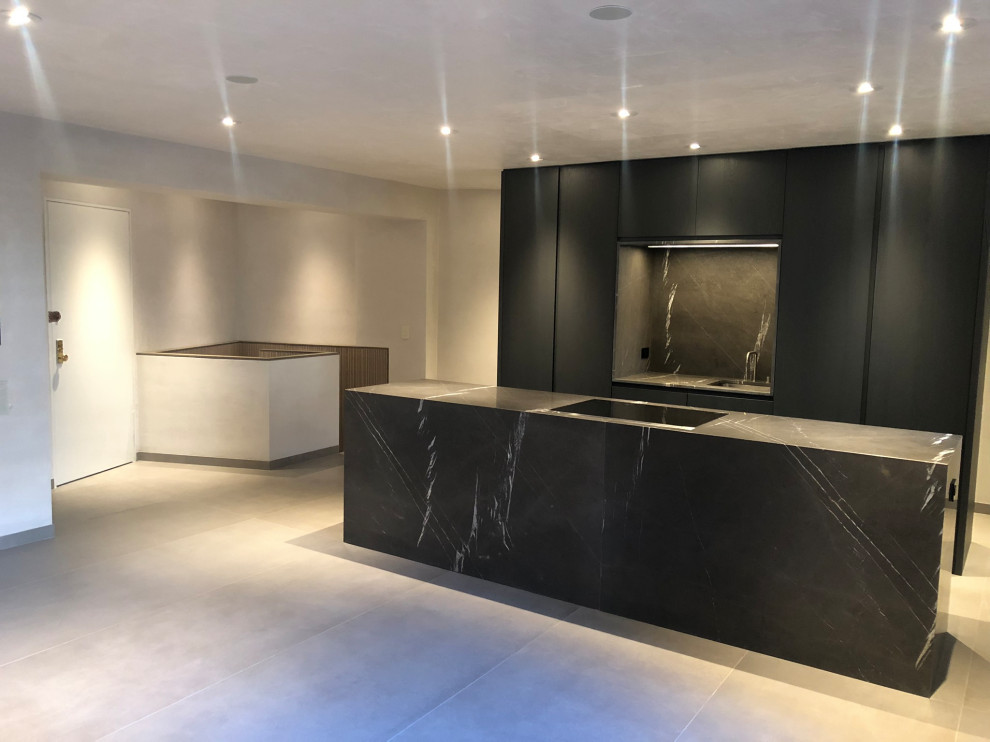 Inspiration for a medium sized contemporary u-shaped kitchen/diner in New York with a submerged sink, flat-panel cabinets, black cabinets, marble worktops, black splashback, stone slab splashback, black appliances, cement flooring, an island, grey floors and black worktops.