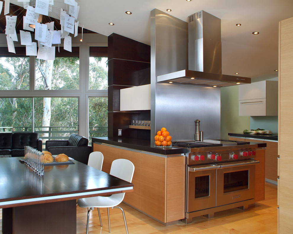 This is an example of a modern open plan kitchen in San Diego with flat-panel cabinets, medium wood cabinets and metallic splashback.