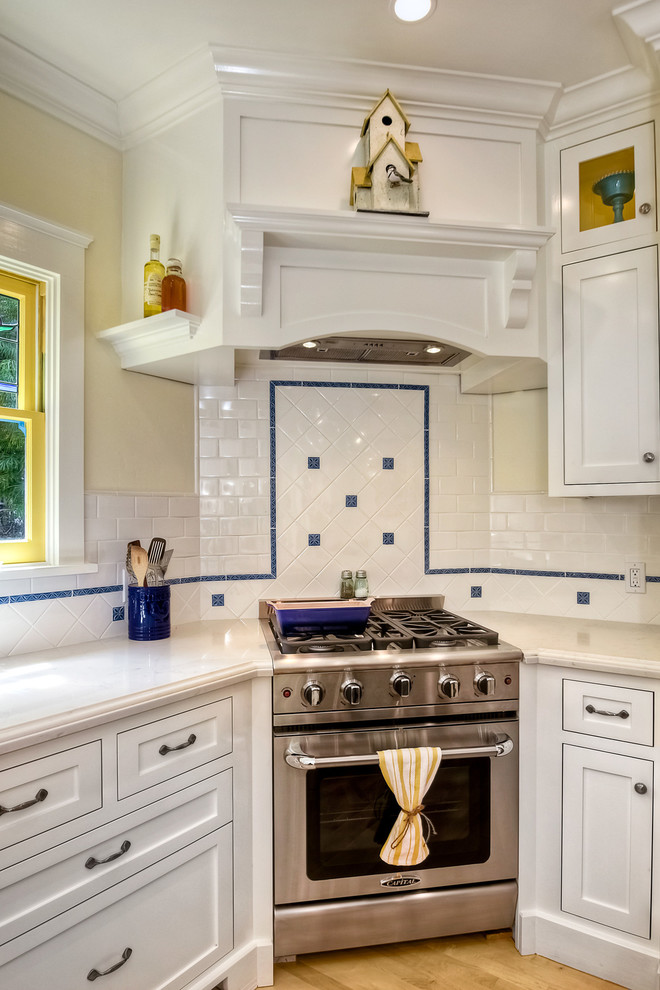 This is an example of a medium sized victorian u-shaped kitchen/diner in San Diego with a submerged sink, recessed-panel cabinets, white cabinets, wood worktops, white splashback, ceramic splashback, stainless steel appliances, light hardwood flooring and an island.