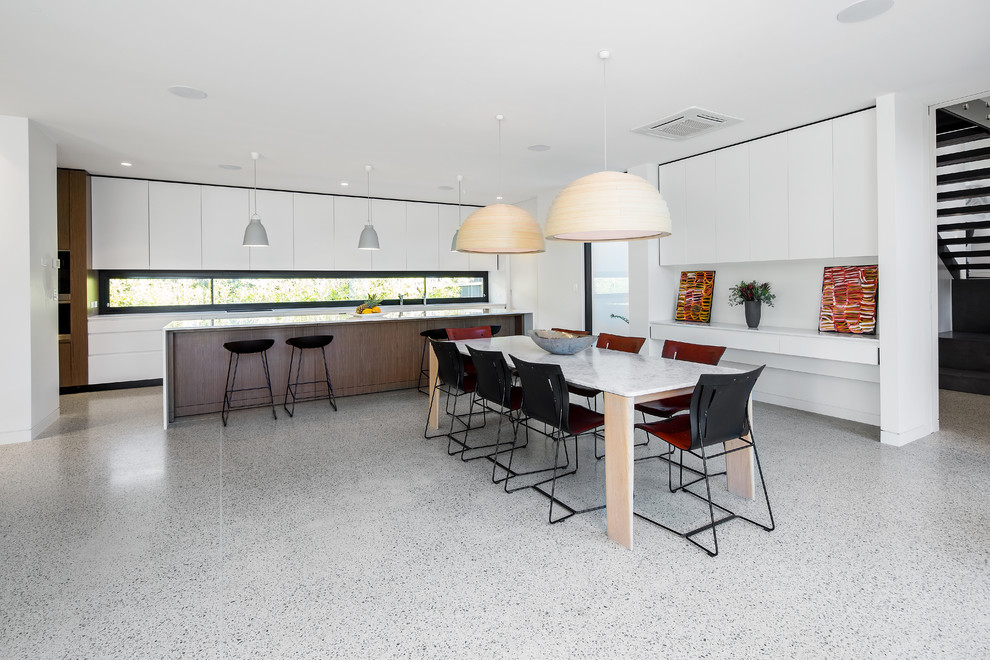 Bild på ett mellanstort funkis kök, med vita skåp, bänkskiva i kvarts, fönster som stänkskydd, rostfria vitvaror, betonggolv, en köksö och vitt golv