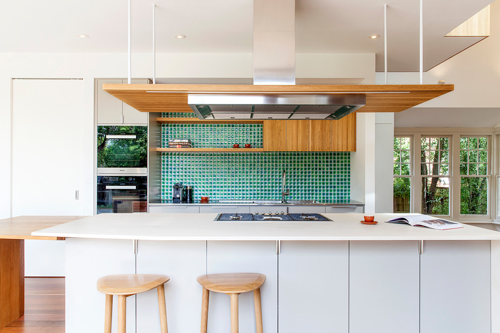 Zweizeilige Moderne Küche mit flächenbündigen Schrankfronten, weißen Schränken, Küchenrückwand in Grün, Küchengeräten aus Edelstahl, braunem Holzboden, Kücheninsel und orangem Boden in Melbourne