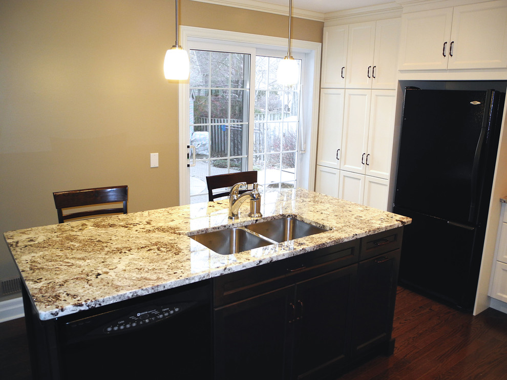 Exempel på ett stort modernt kök, med en dubbel diskho, luckor med infälld panel, vita skåp, granitbänkskiva, vitt stänkskydd, stänkskydd i keramik, svarta vitvaror, mörkt trägolv och en köksö