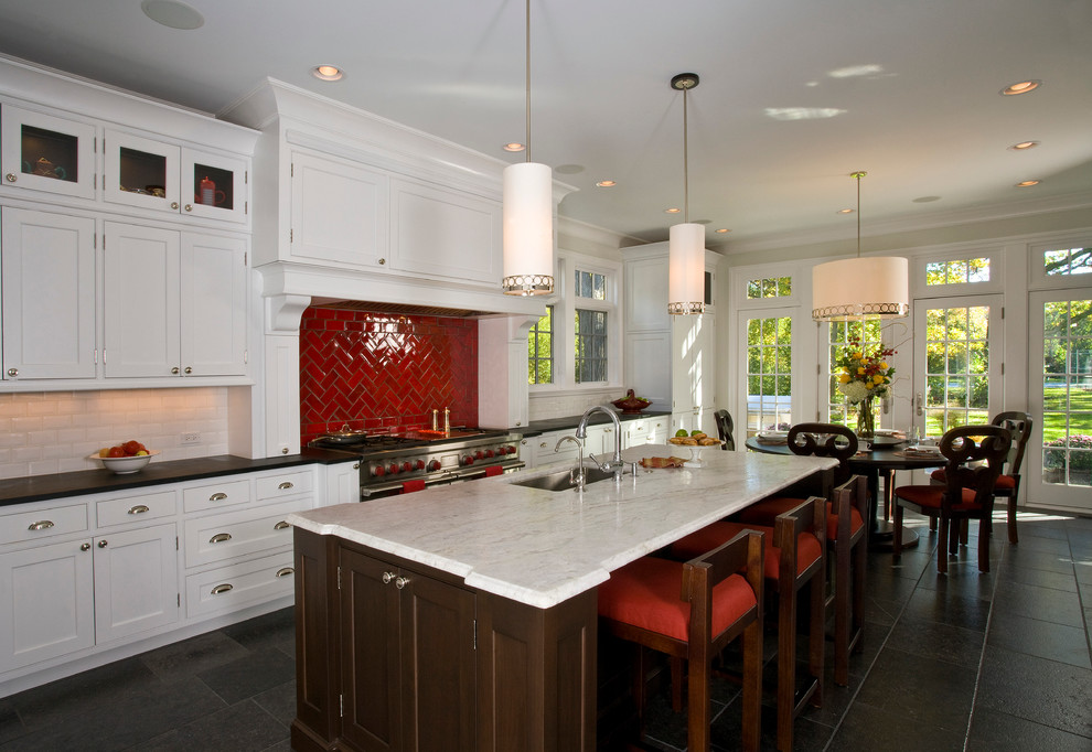 Exempel på ett stort klassiskt linjärt kök och matrum, med en undermonterad diskho, luckor med infälld panel, vita skåp, marmorbänkskiva, rött stänkskydd, stänkskydd i porslinskakel, skiffergolv, en köksö och svart golv