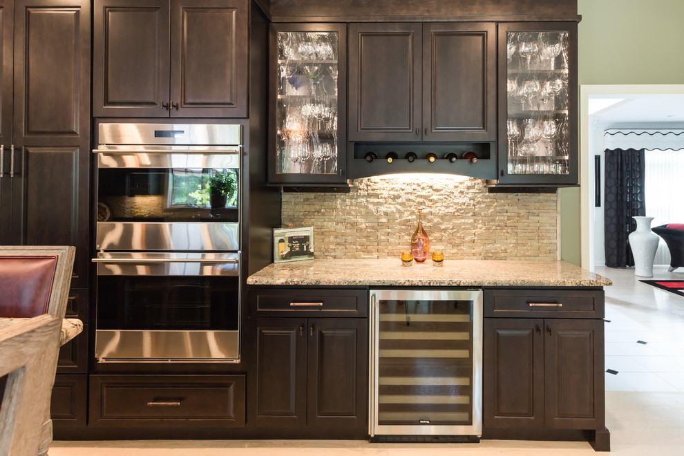 Example of a large tuscan u-shaped light wood floor eat-in kitchen design in New York with a single-bowl sink, raised-panel cabinets, dark wood cabinets, granite countertops, beige backsplash, stone tile backsplash, stainless steel appliances and an island