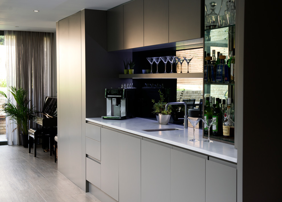Modern inredning av ett kök med öppen planlösning, med släta luckor, grå skåp, marmorbänkskiva, spegel som stänkskydd, klinkergolv i porslin och grått golv
