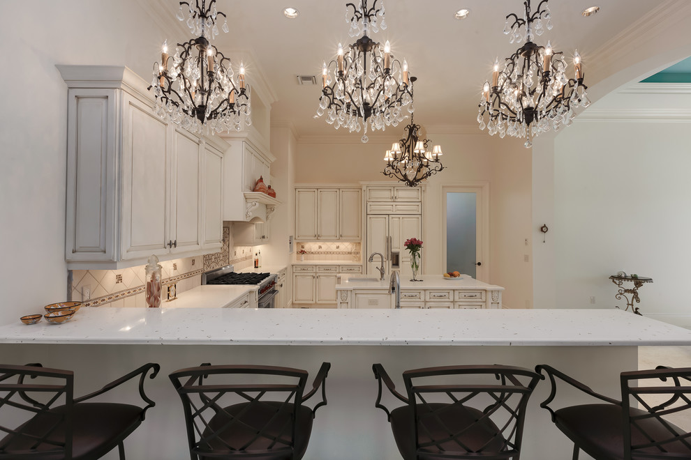 Inspiration for a large timeless u-shaped marble floor kitchen pantry remodel in Tampa with an island, an undermount sink, raised-panel cabinets, white cabinets, marble countertops, white backsplash, ceramic backsplash and stainless steel appliances