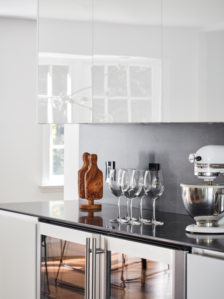 Bild på ett stort funkis svart svart kök och matrum, med en undermonterad diskho, luckor med glaspanel, vita skåp, svart stänkskydd, rostfria vitvaror, mörkt trägolv, en köksö och brunt golv