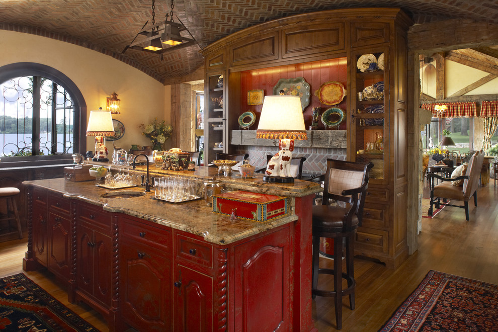 На фото: кухня в стиле рустика с фасадами с выступающей филенкой, гранитной столешницей, красными фасадами и барной стойкой с