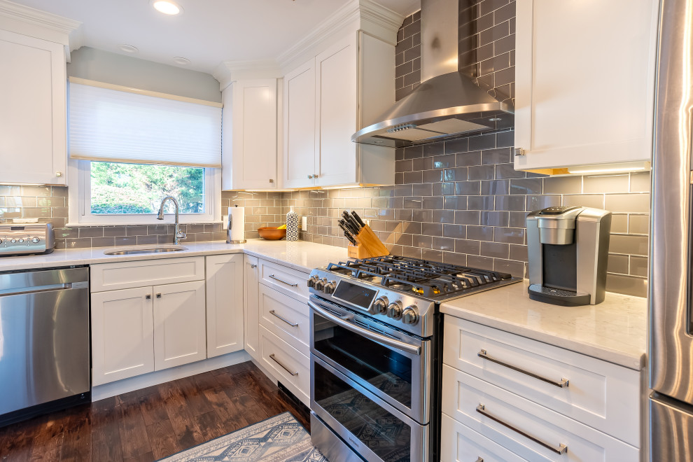 Foto på ett stort vintage flerfärgad kök, med en undermonterad diskho, skåp i shakerstil, vita skåp, bänkskiva i kvarts, grått stänkskydd, stänkskydd i tunnelbanekakel, rostfria vitvaror, mellanmörkt trägolv, en köksö och vitt golv