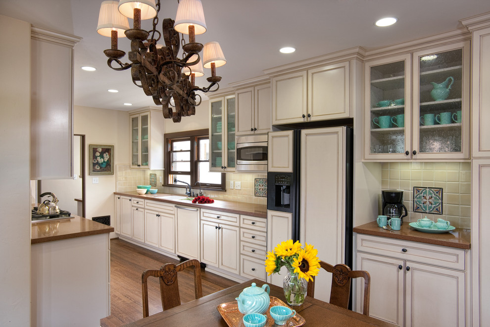 Example of a tuscan medium tone wood floor kitchen design in San Diego with a double-bowl sink, raised-panel cabinets, white cabinets, marble countertops, beige backsplash, ceramic backsplash, no island and paneled appliances