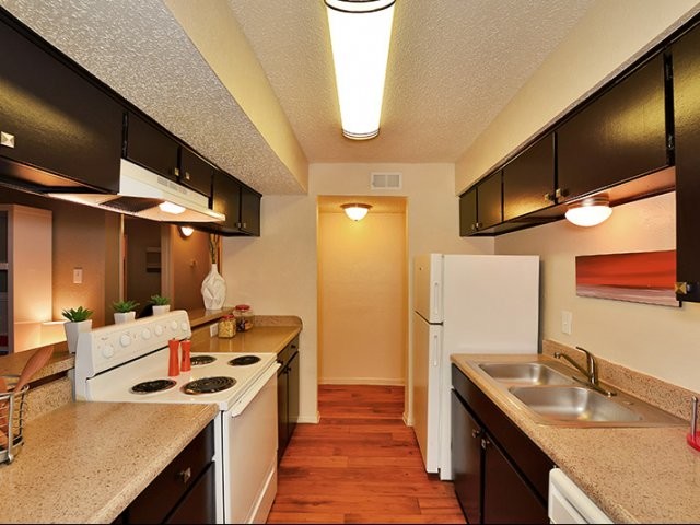 Medium sized traditional galley kitchen/diner in Austin with a built-in sink, flat-panel cabinets, brown cabinets, laminate countertops, multi-coloured splashback, white appliances, bamboo flooring and no island.