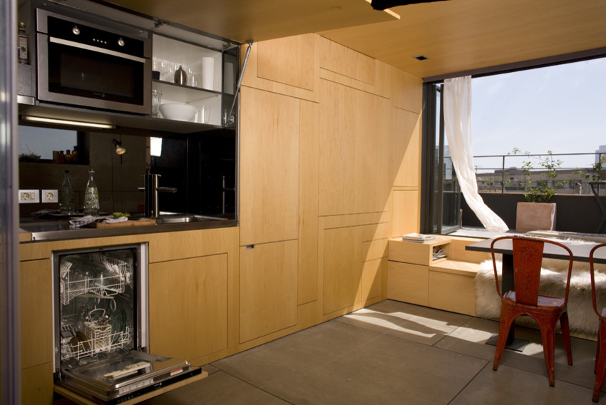 Diseño de cocina comedor lineal actual con armarios con paneles lisos, puertas de armario de madera clara y electrodomésticos con paneles