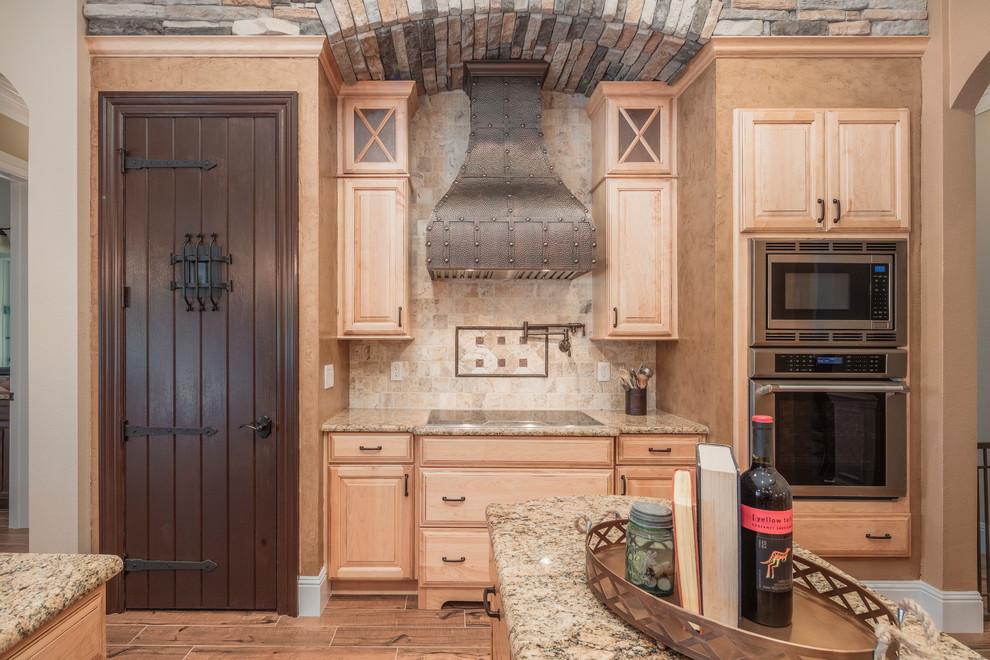 Example of a large tuscan u-shaped kitchen design in Orlando with a farmhouse sink, raised-panel cabinets, medium tone wood cabinets, stone tile backsplash, stainless steel appliances and an island